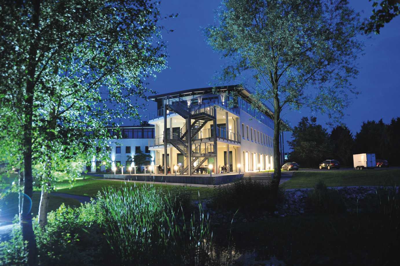Gebäude mit Lichtern im Dunkeln mit viel Garten